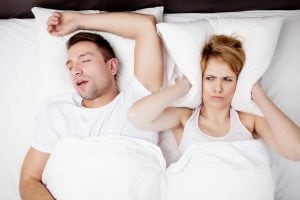 man snoring in bed keeping his wife up