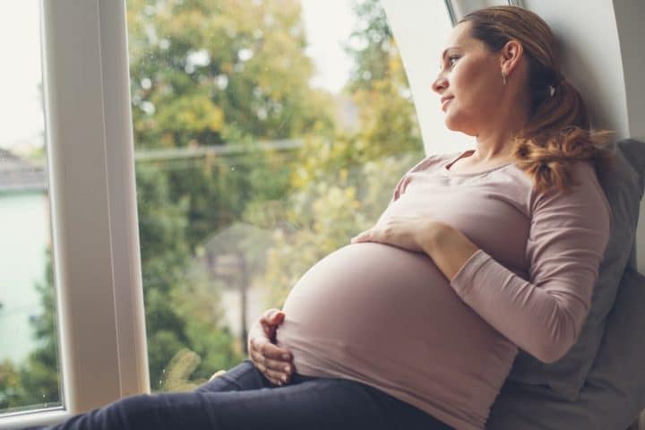 pregnant woman staring out a window