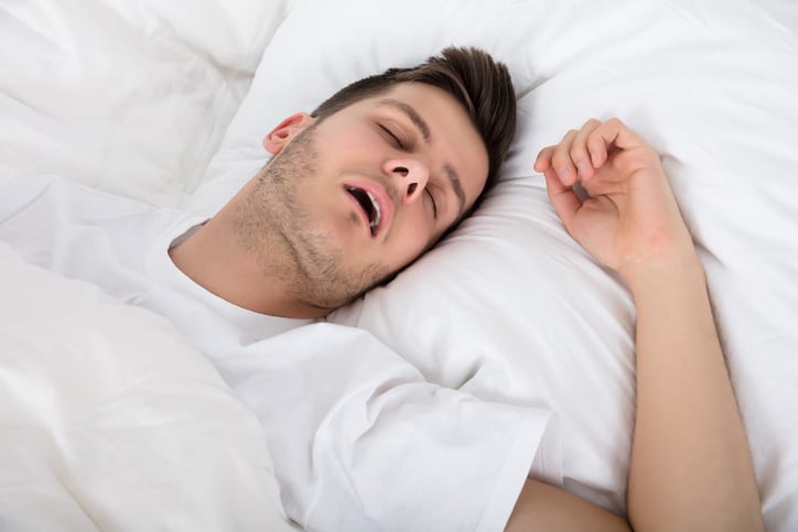 View Of Tired Young Man Snoring While Deep Sleeping In Bed