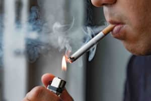 Close up young man smoking a cigarette