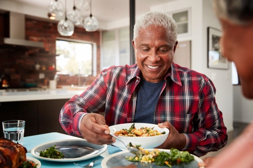 Senior Couple Enjoying Meal Around Table At Home