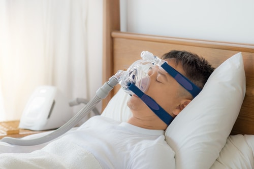 man wearing cpap mask sleeping smoothly on his back pillow high without snoring